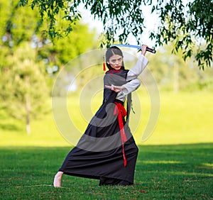 Young asian woman in traditional kimono trains fighting techniques with katana sword samurai warrior girl