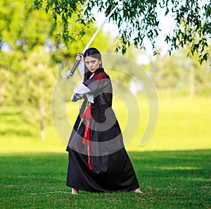 Young asian woman in traditional kimono trains fighting techniques with katana sword samurai warrior girl