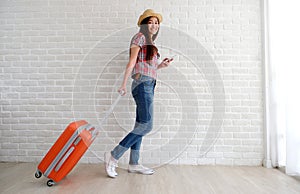 Young asian woman traveler holding smart phone and  luggage in white room with copy space, people summer holiday vacation