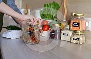 Young Asian woman twists the lid on a glass jar. Pasta from durum wheat