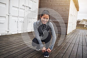 Young Asian woman tying her running shoes before a run