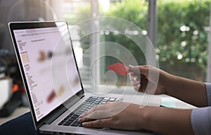 Young asian woman typing laptop keyboard and holding credit card at home with online shopping or internet banking concept