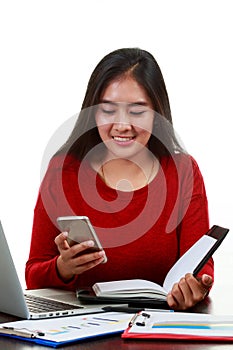 Young Asian woman typing the memo while checking sale volume graph with smiling