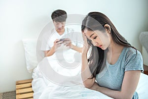 Young asian woman is upset that man uses phone all the time without paying attention to her. Man holds phone pay attention on