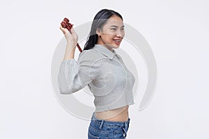 A young asian woman using a backscratcher. Using a convenient toll to scratch her back. Isolated on a white background