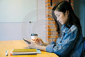 Young asian woman using digital tablet at home office background, casual office life, Asian female and digital tablet while