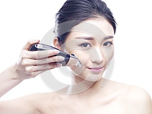 Young asian woman using a face spa device