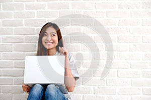 Young asian woman using laptop computer sitting in front of whit