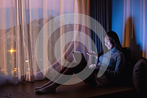 A young asian woman using laptop computer for video call with bright light screen in the late night at home