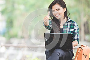 Young asian woman using laptop while sitting on the park