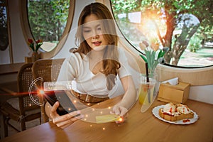 Young Asian woman using mobile phone, holding credit card for online shopping product in cafe and paying bills with banking app