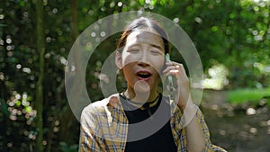 Young asian woman using mobile phone talking with friend in rainforest