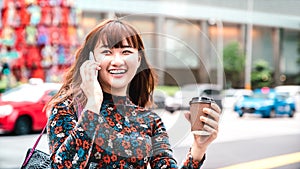 Young asian woman using mobile smart phone at Singapore city streets - Technology life style concept with happy girl having fun