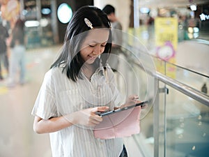 Young asian woman using a portable computer or tablet while standing in a shopping center