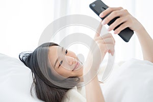 Young Asian woman using smart phone in bedroom happy and smile..