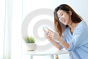 Young asian woman using smart phone with relax emotion on white