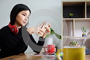 Young asian woman using smart phone while sitting in home office