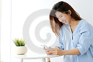 Young asian woman using smart phone with smiling, happy and relax emotion in white room background, people on phone, lifestyle