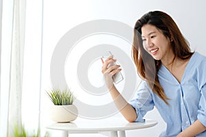 Young asian woman using smart phone with smiling, happy and relax emotion in white room background, people on phone, lifestyle