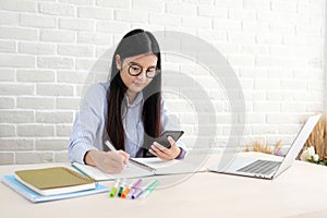 Young asian woman using smart phone while working at her office