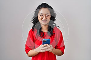 Young asian woman using smartphone typing message smiling with a happy and cool smile on face