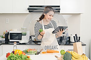 Young asian woman using a tablet computer to cook in her kitchen