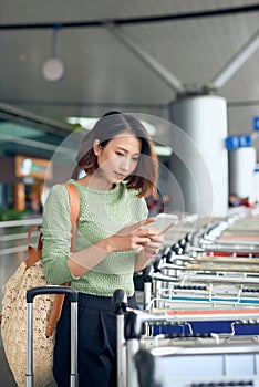 Young Asian woman waiting on the side of the street for her ride that she booked via a ride-hailing app photo