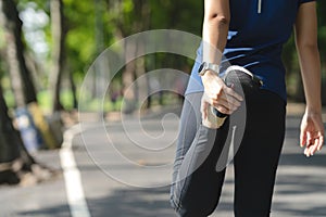 Young asian woman warm up before workout or cool down after running in nature public city park. Cardio sport for weight lose in