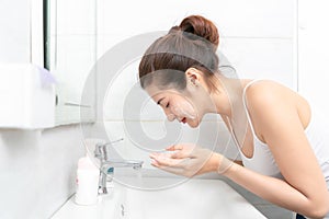 Young Asian woman washing her face in bathroom