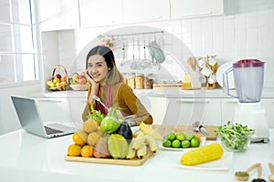 Young asian woman watching online training in the kitchen at home