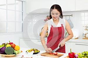 Young Asian woman wearing an apron in the kitchen preparing to cook