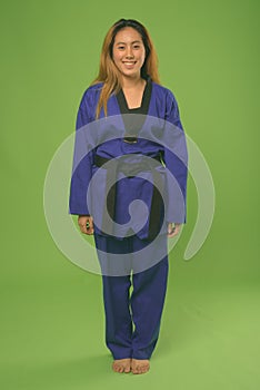 Young Asian woman wearing blue karate Gi against green background