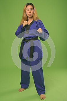 Young Asian woman wearing blue karate Gi against green background