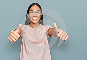 Young asian woman wearing casual clothes approving doing positive gesture with hand, thumbs up smiling and happy for success