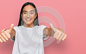 Young asian woman wearing casual white t shirt approving doing positive gesture with hand, thumbs up smiling and happy for success