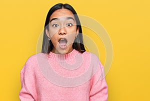 Young asian woman wearing casual winter sweater afraid and shocked with surprise and amazed expression, fear and excited face