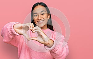 Young asian woman wearing casual winter sweater smiling in love doing heart symbol shape with hands