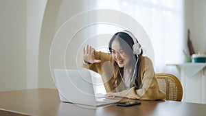 Young asian woman wearing glasses and headset working on computer laptop at house