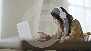 Young asian woman wearing glasses and headset working on computer laptop at house