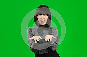 Young Asian woman wearing gray shirt posing like show something on green screen