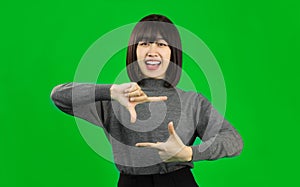 Young Asian woman wearing gray shirt standing and looking at camera isolated on green screen