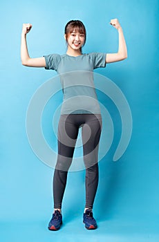 Young asian woman wearing gym suit on blue background