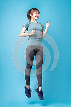 Young asian woman wearing gym suit on blue background