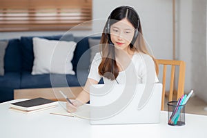 Young asian woman wearing headphone study online with e-learning on desk, girl wearing headset learning to internet.