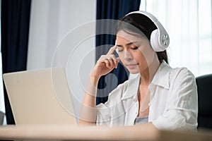 Young asian woman wearing headset working on computer laptop at house