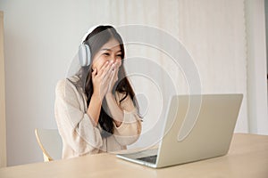 Young asian woman wearing headset while working on computer laptop at house