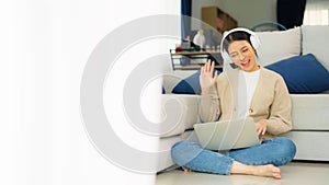 Young asian woman wearing headset while working on computer laptop at house