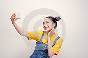 Young Asian woman wearing a jeans dungaree who taking selfie and smiling