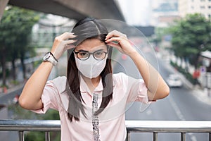 Young Asian woman wearing N95 respiratory mask protect and filter pm2.5 particulate matter against traffic and dust city.