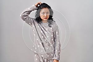 Young asian woman wearing pajama confuse and wonder about question